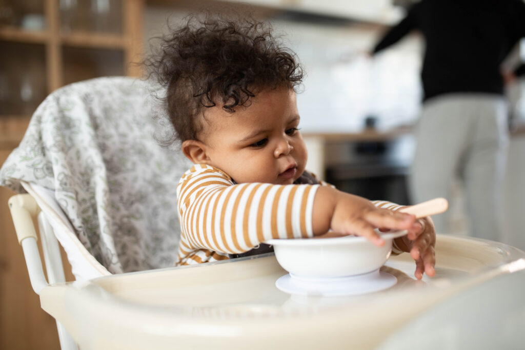 Infant learning to eat from a bowl.